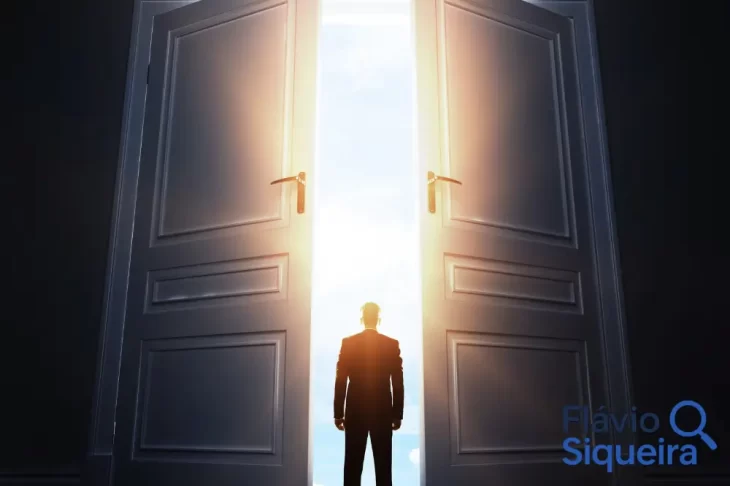 Silhueta de homem em frente a portas abertas com luz intensa ao fundo, representando o início de um pequeno negócio e o caminho empreendedor com baixo investimento.