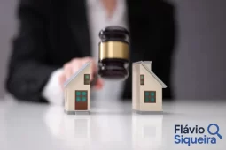 Miniaturas de casas sendo separadas por um martelo de juiz, representando a divisão de bens em processos de separação ou inventário.
