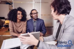 Casal sendo orientado por consultora financeira sobre o melhor investimento hoje, com logo Flávio Siqueira no canto da imagem.