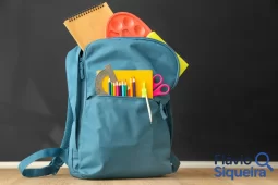 Mochila azul com cadernos, lápis e outros itens de material escolar organizados.