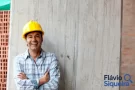 Trabalhador com capacete sorrindo ao lado de uma parede de concreto, simbolizando renda extra.