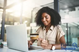 Mulher usando notebook e segurando um cartão, simbolizando o limite do rotativo do cartão de crédito.