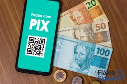 Celular com QR Code do Pix ao lado de dinheiro, simbolizando segurança no Pix.